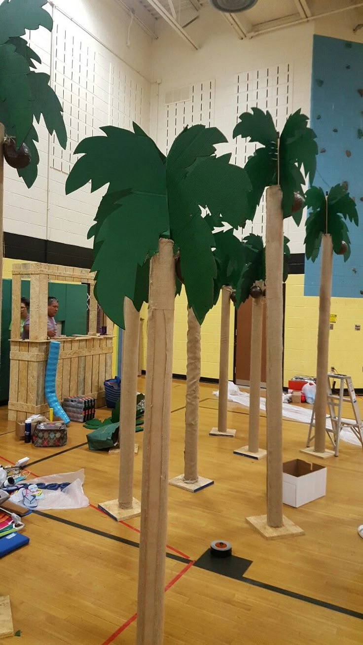 several palm trees are in the middle of a gym with construction materials on the floor