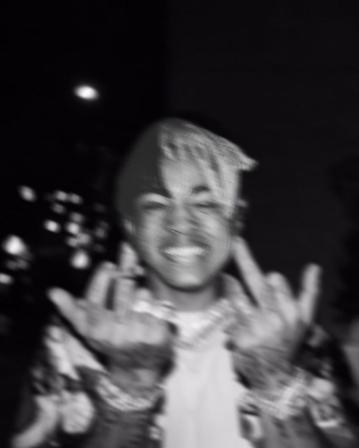 a black and white photo of a man making the peace sign with his hands in front of him