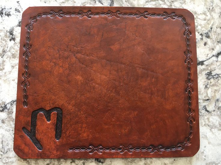 a brown leather placemat with a hand - stitched design on the front and side