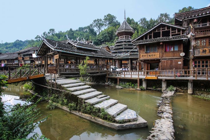 an old wooden building with steps leading up to the water in front of some buildings