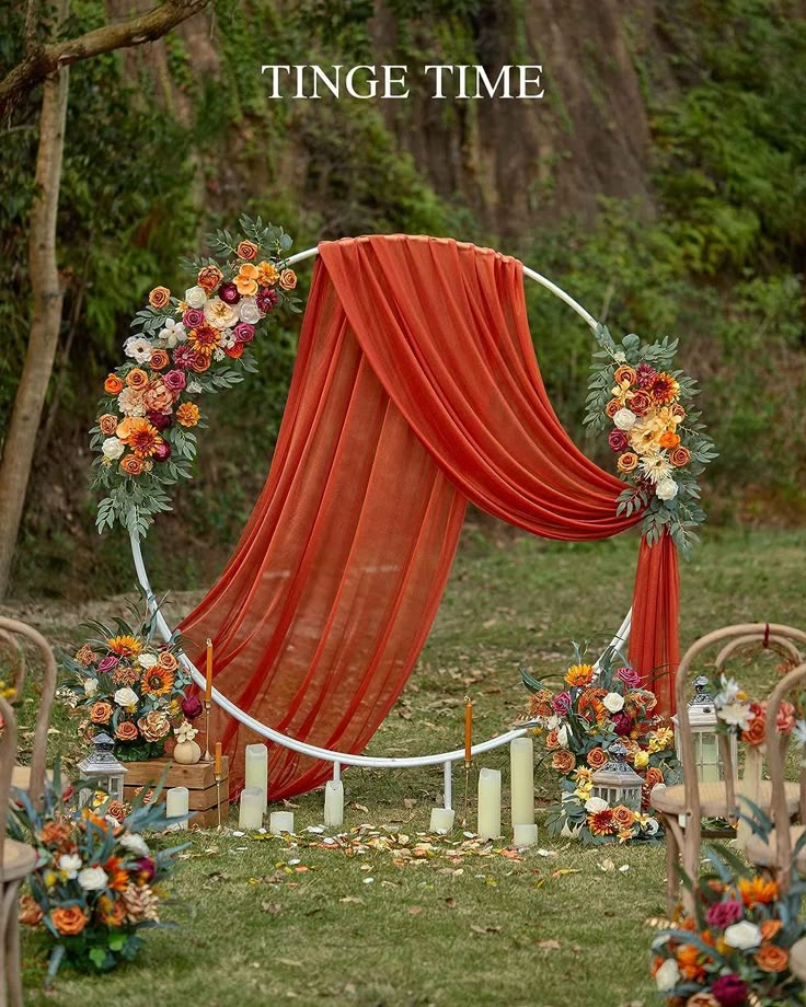 an outdoor wedding set up with orange drapes and flowers