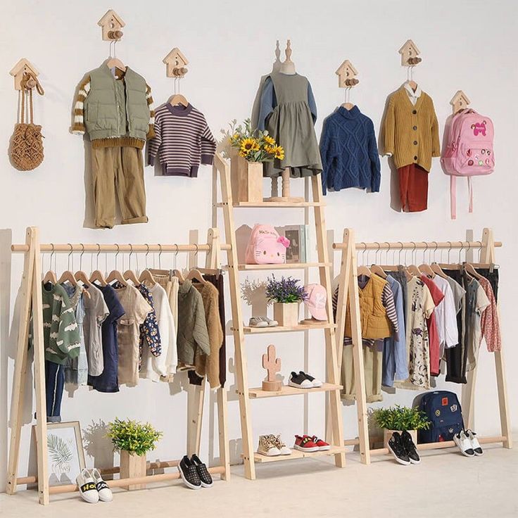 an assortment of children's clothing hanging on wooden racks