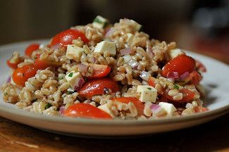 a plate full of rice, tomatoes and other vegetables on top of a wooden table