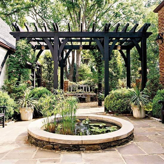 an outdoor garden with a pond and pergolated seating area, surrounded by greenery