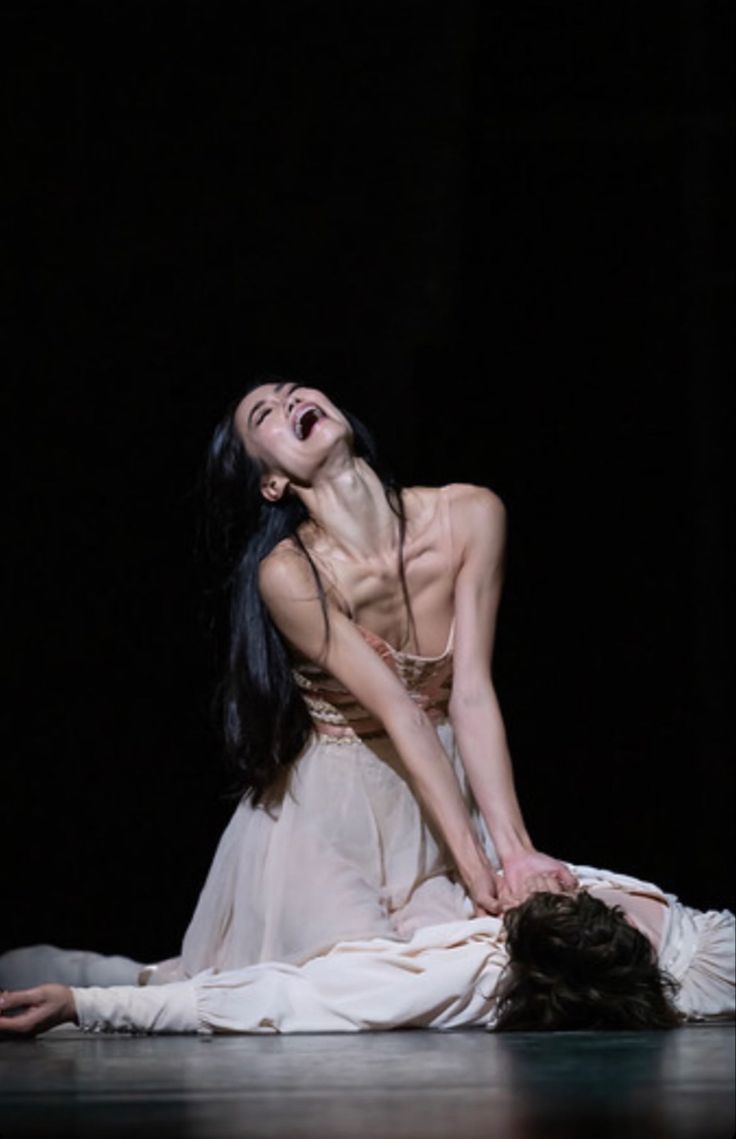 a woman in white dress laying on the ground with her head down and hands behind her back