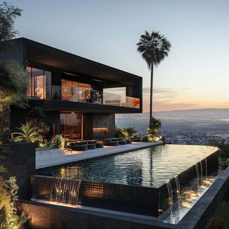 a large pool in front of a modern house with palm trees and mountains behind it