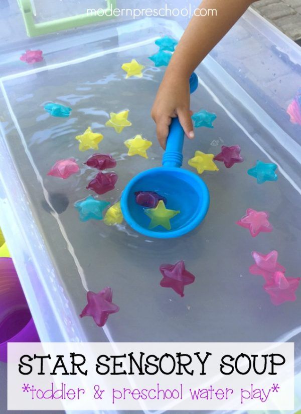 a child is playing with star sensory soup in a plastic container filled with water