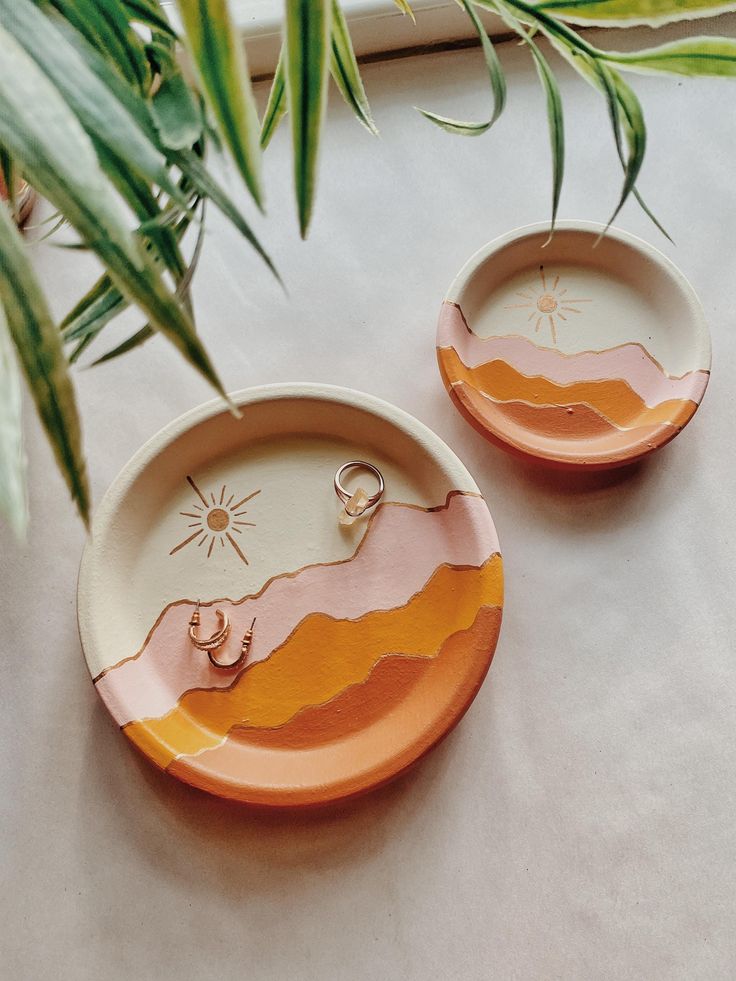 two orange and white plates sitting on top of a table next to a potted plant