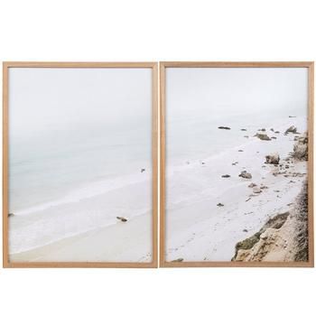 two framed photographs of the ocean and beach in front of them, one is empty