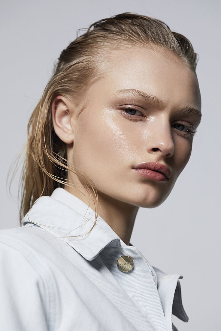 a woman with blonde hair wearing a white shirt and gold buttons on her collar, looking at the camera