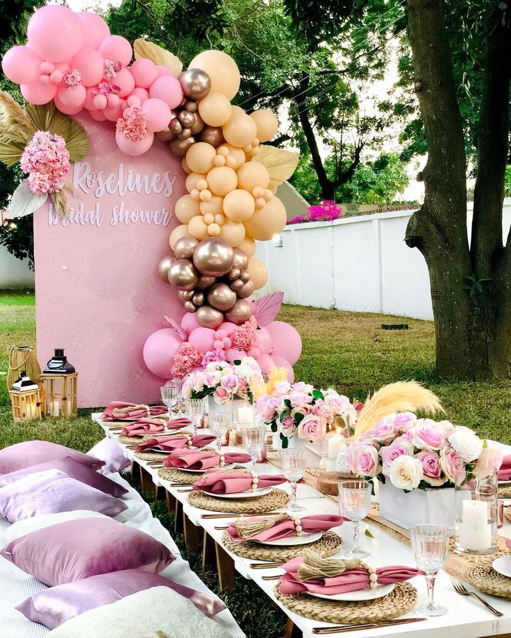 a table set up with pink and gold balloons