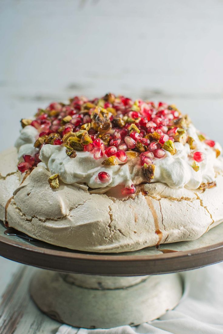 a cake with white frosting and pomegranates on top sitting on a plate