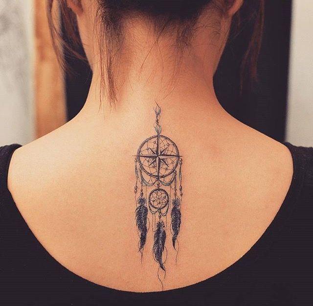 a woman with a tattoo on her back has a compass and a dream catcher in it