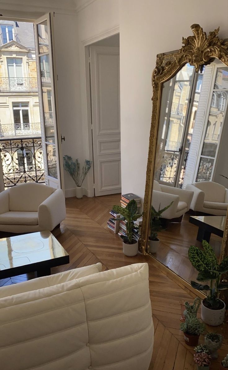 a living room filled with furniture and a large mirror on the wall next to it