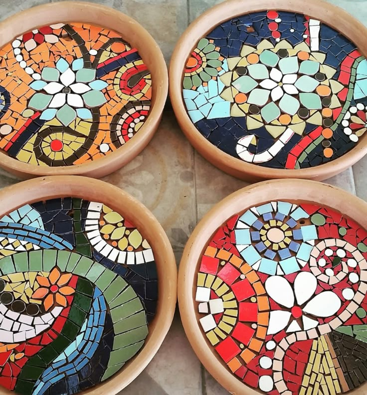 four bowls with colorful designs on them sitting on a tile floor next to each other