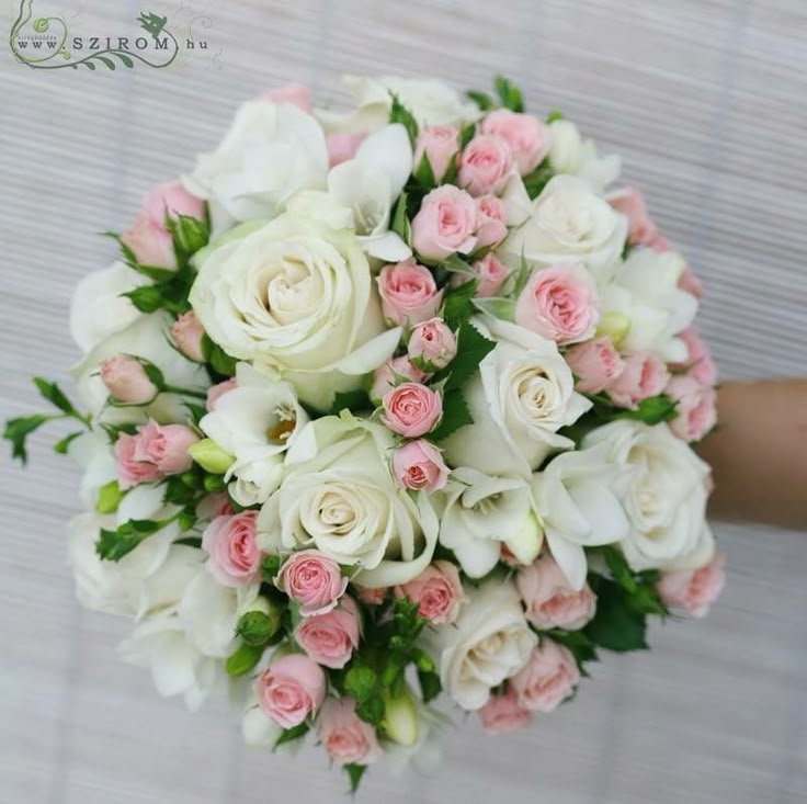 a bouquet of white and pink flowers is held by someone's hand on the floor