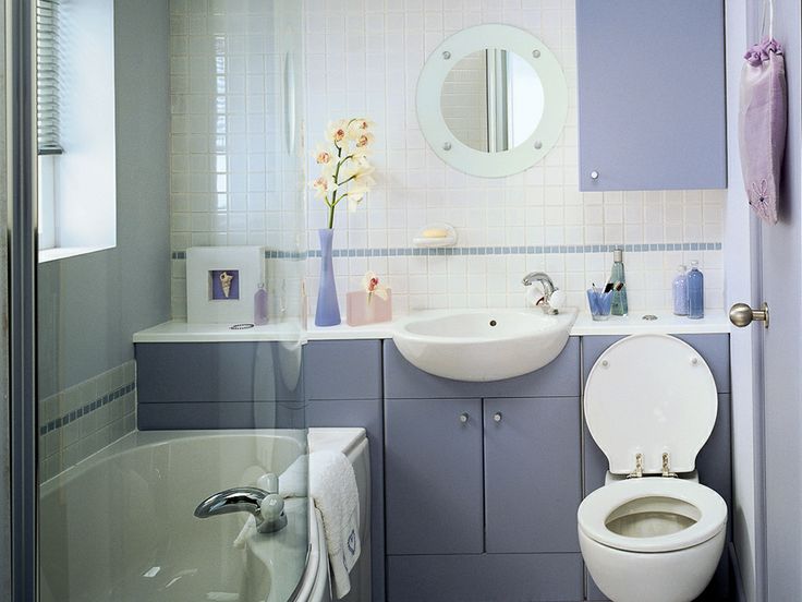 a white toilet sitting next to a bath tub under a bathroom mirror above a sink