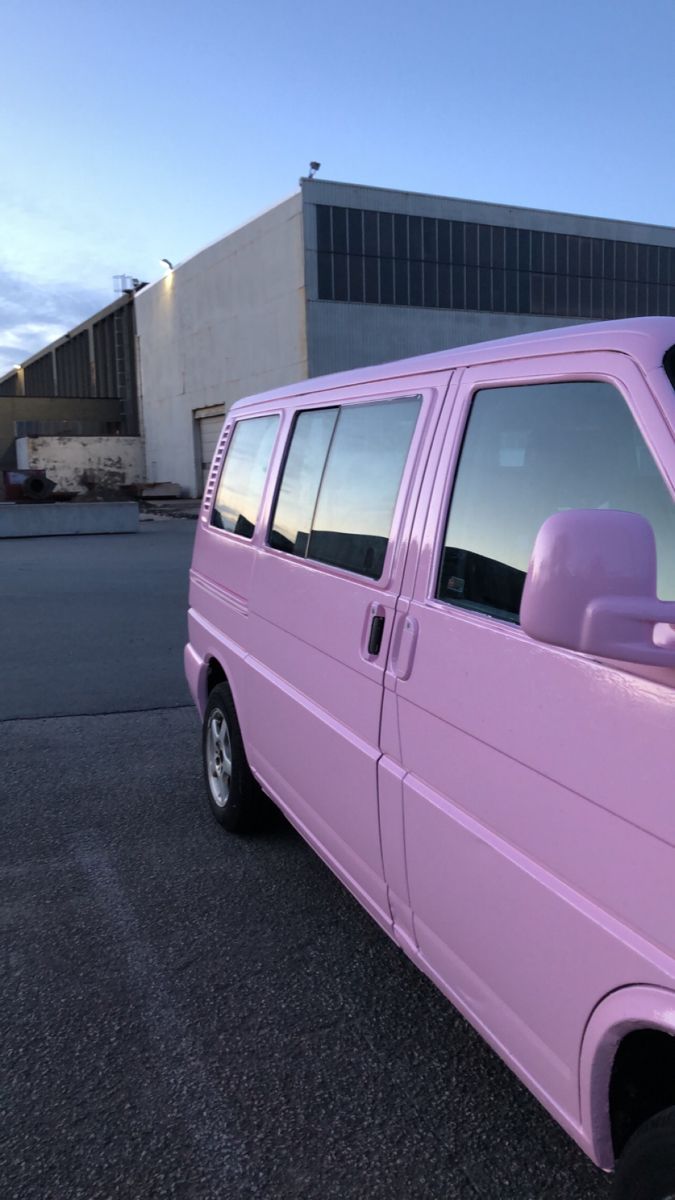 a pink van parked in front of a building