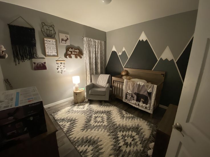 a baby's room with mountains painted on the wall and a crib in the corner