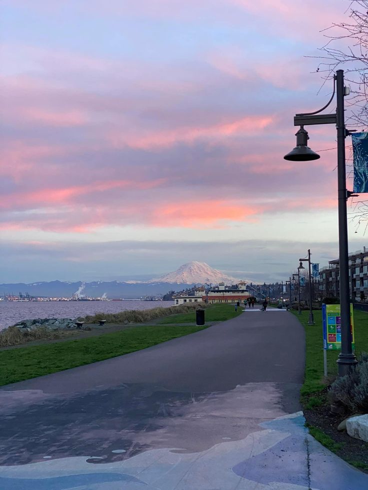 a street sign on the side of a road next to a body of water with mountains in the background