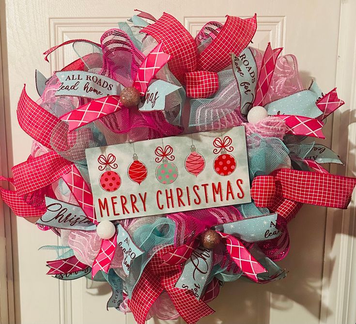 a christmas wreath on the front door decorated with red and blue ribbons, ornaments and words