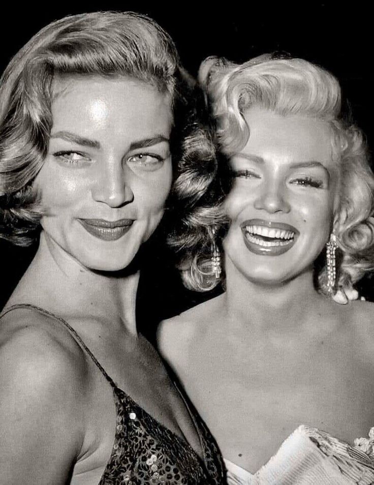 black and white photograph of two women in evening dresses smiling at the camera with their arms around each other