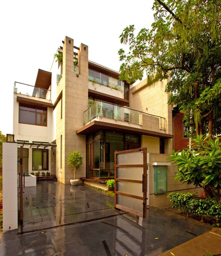 a large house with an open garage door on the front and side of it, surrounded by greenery