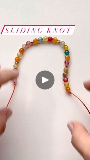 two hands are making a beaded necklace