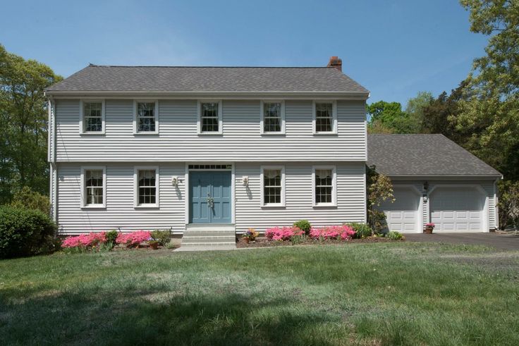 a two story house with white siding and blue door