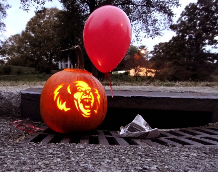 two pumpkins that have been carved to look like bears with balloons in the background