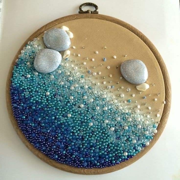 an embroidery project with blue and white beads on the bottom, two rocks in the middle