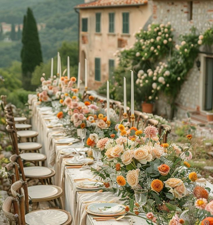 a long table is set with flowers and candles for an outdoor wedding reception in the countryside