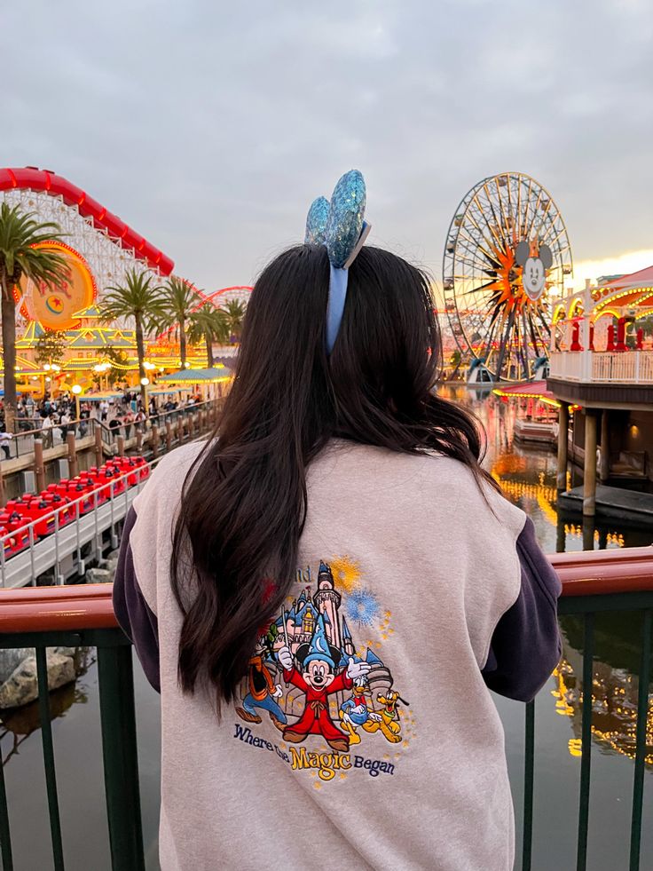 a woman is looking out over the water at an amusement park