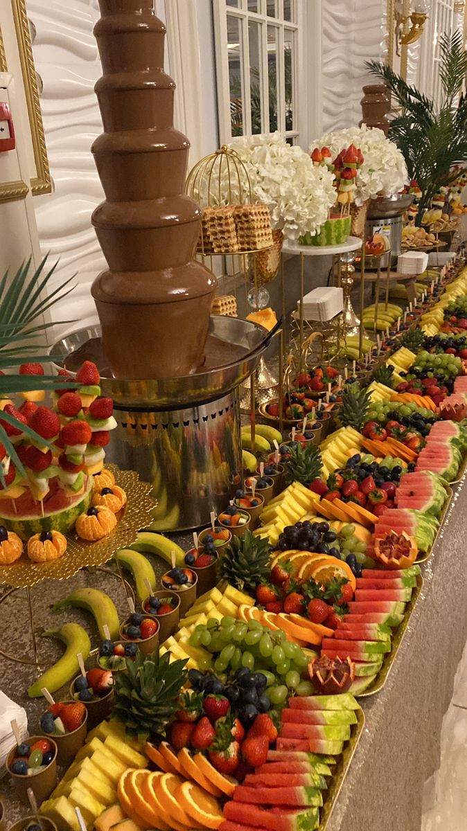 a buffet table filled with lots of fruit and chocolate fountain on top of the tables