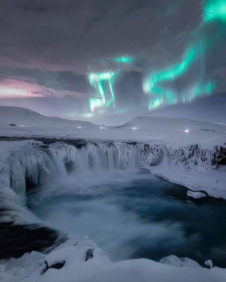 the aurora lights shine brightly in the sky above a frozen waterfall