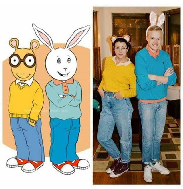 a man and woman standing next to each other in front of a cartoon character wearing bunny ears