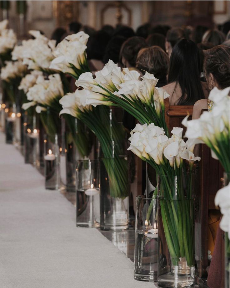 rows of vases filled with white flowers on a table