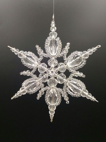 a crystal snowflake ornament hanging on a black background