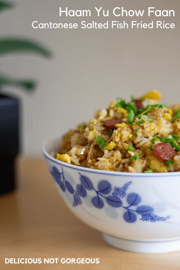 a bowl filled with rice and vegetables on top of a wooden table next to a potted plant