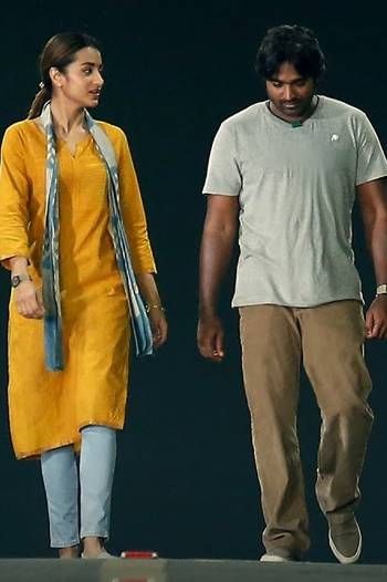 a man and woman are walking together on a dark background, one is wearing a yellow dress