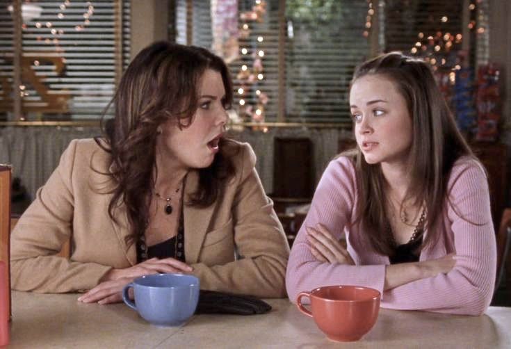 two women sitting at a table with cups in front of them