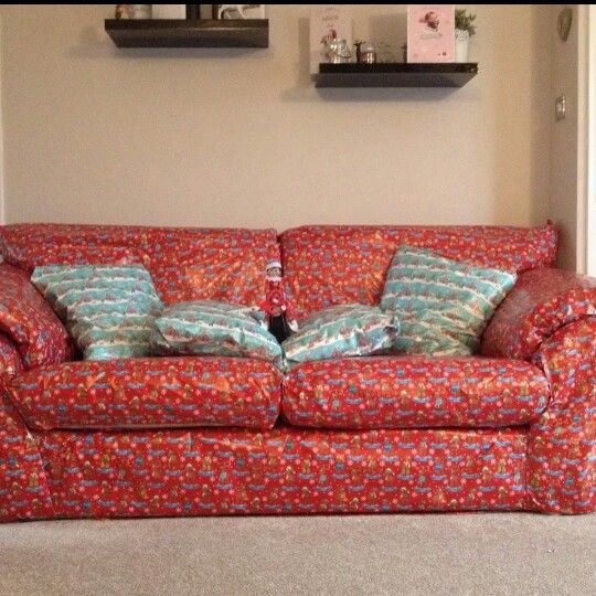 a red couch with two pillows on top of it in front of a wall mounted shelf