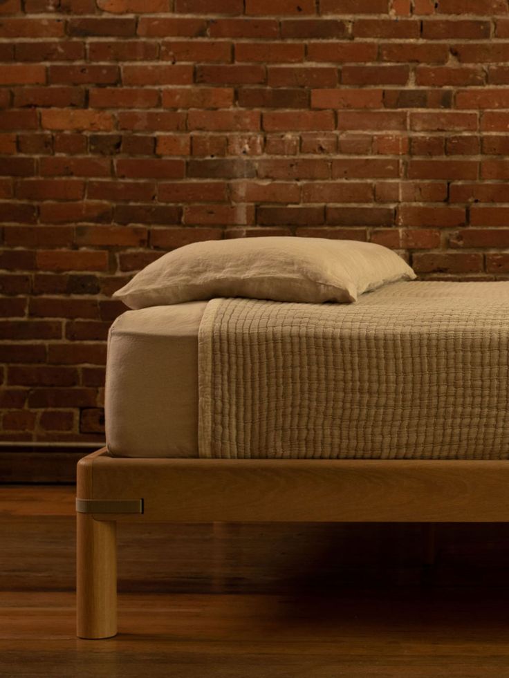 a bed that is in front of a brick wall