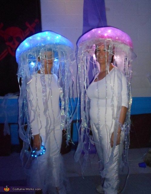 two women dressed in white are standing next to each other with jelly hats on their heads