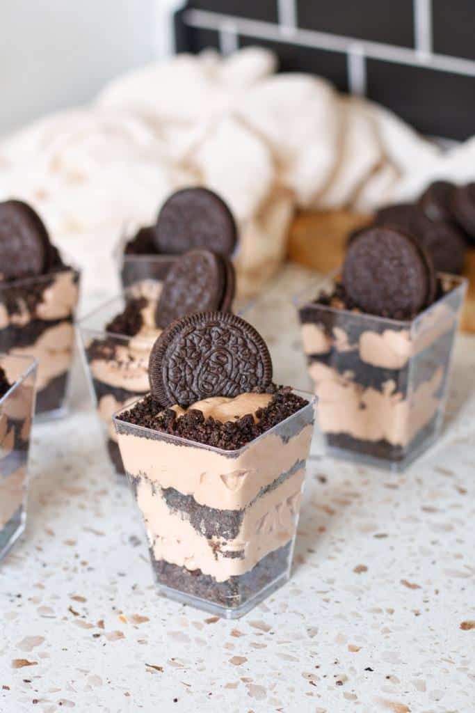 oreo cookies and ice cream desserts in small cups on a table with white linen