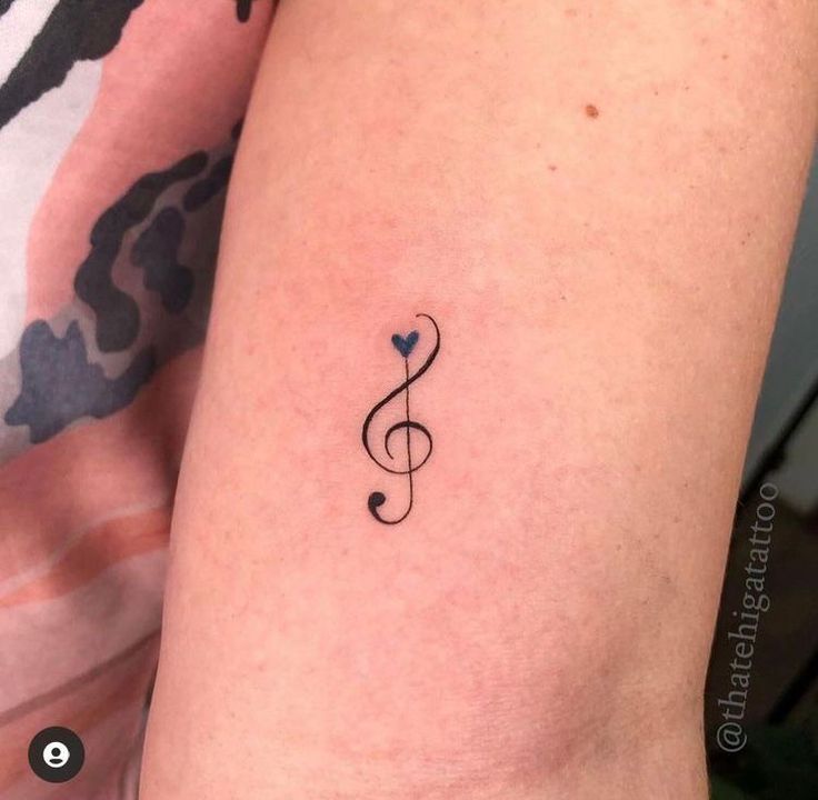 a tattoo with a treble on the arm and a small heart in the middle