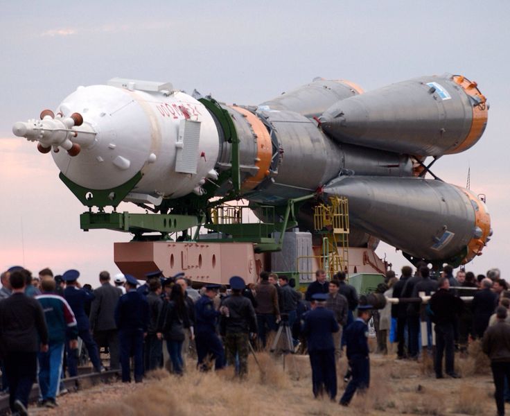 people are gathered around a large rocket on display