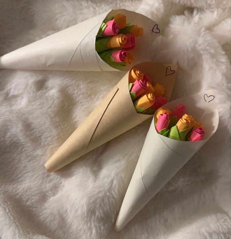 two cones with flowers in them sitting on a white blanket