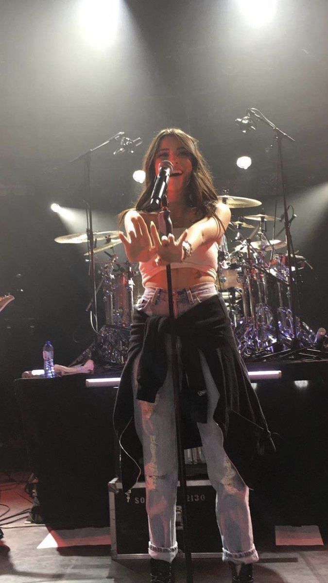 a woman standing on top of a stage holding a microphone in front of her face