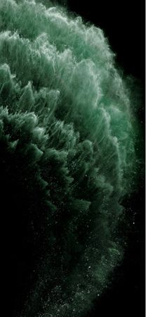 the water is green and white as it splashes into the air on a black background